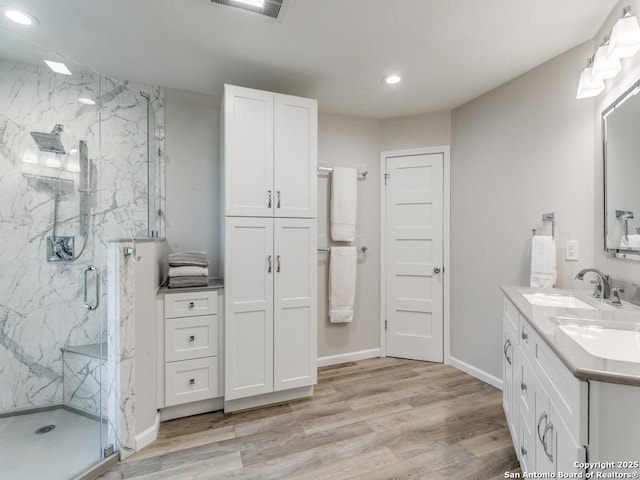 13907 Bluffmont, San Antonio, TX 78216 - full bath with double vanity, wood finished floors, recessed lighting, a sink, and a marble finish shower