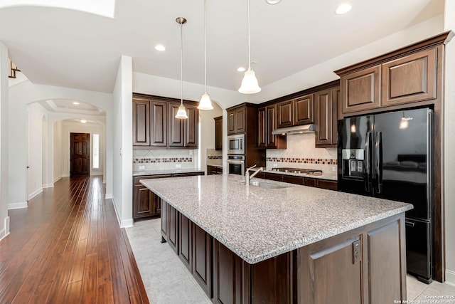 2623 Galit Cv, San Antonio, TX 78230 - kitchen featuring dark brown cabinetry, appliances with stainless steel finishes, a sink, arched walkways, and under cabinet range hood