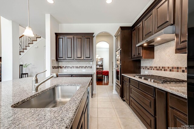 2623 Galit Cv, San Antonio, TX 78230 - kitchen featuring dark brown cabinetry, appliances with stainless steel finishes, tasteful backsplash, a sink, and under cabinet range hood