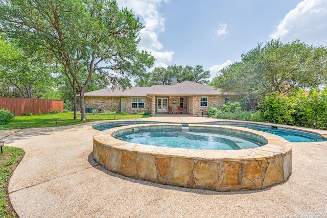 outdoor pool with fence, an in ground hot tub, and a yard