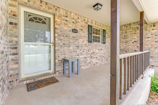 view of exterior entry with brick siding and covered porch