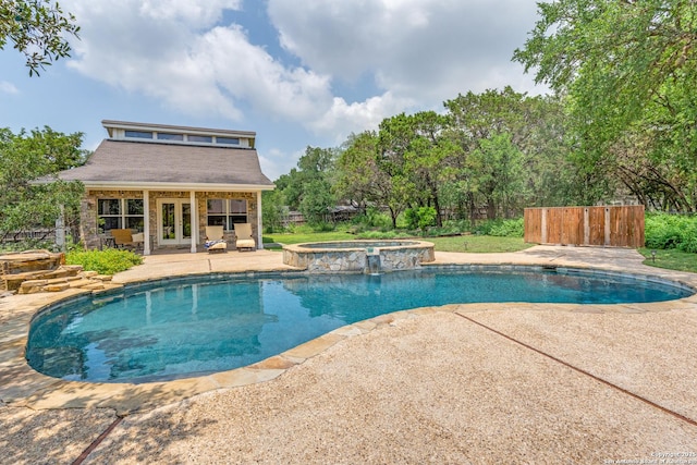 view of pool featuring fence, a pool with connected hot tub, an outbuilding, a patio area, and french doors