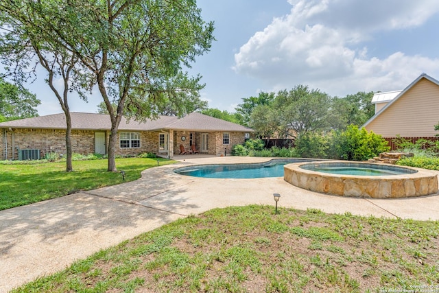 view of pool with a lawn, central AC unit, a pool with connected hot tub, and a patio