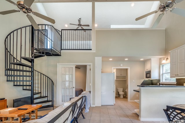 interior space featuring light tile patterned floors, a high ceiling, stairway, and a ceiling fan
