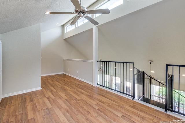 additional living space featuring baseboards, ceiling fan, high vaulted ceiling, and wood finished floors