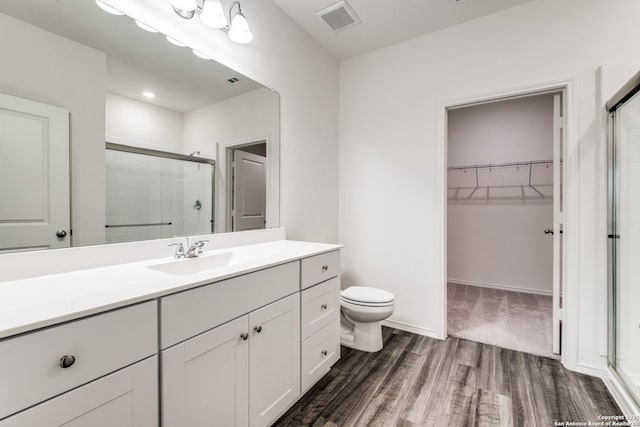 5014 Jovian, San Antonio, TX 78245 - full bathroom featuring visible vents, vanity, wood finished floors, a walk in closet, and a shower stall