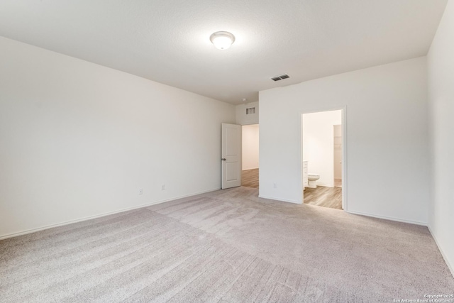 5014 Jovian, San Antonio, TX 78245 - unfurnished bedroom featuring visible vents, baseboards, ensuite bathroom, and light colored carpet