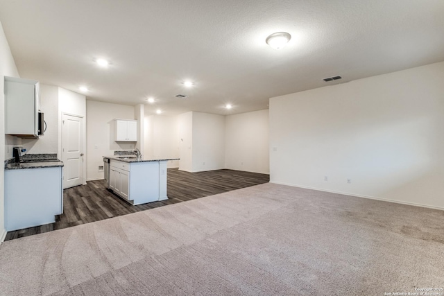 5014 Jovian, San Antonio, TX 78245 - kitchen featuring a kitchen island with sink, dark countertops, white cabinets, open floor plan, and recessed lighting