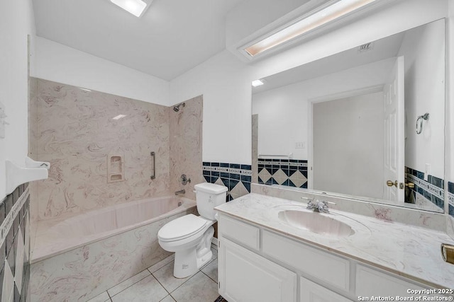 bathroom featuring tile patterned flooring, vanity, toilet, a wainscoted wall, and tile walls