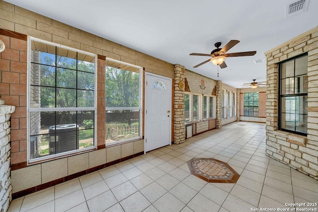 unfurnished sunroom featuring visible vents, tile patterned flooring, and a healthy amount of sunlight