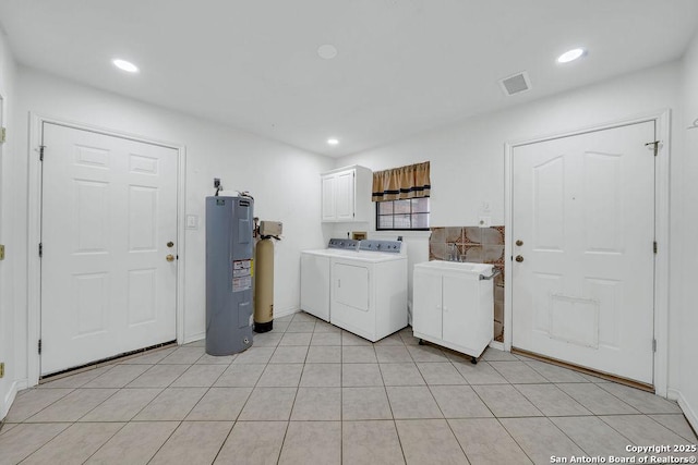 laundry area featuring cabinet space, light tile patterned flooring, washing machine and clothes dryer, water heater, and visible vents