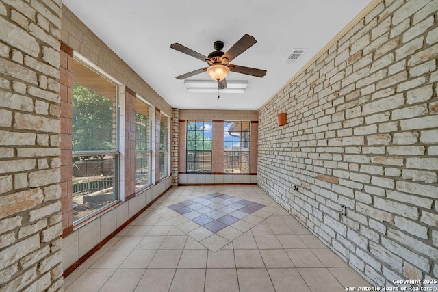 unfurnished sunroom with tile patterned floors, brick wall, and visible vents