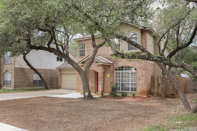 traditional home featuring brick siding, driveway, fence, and a garage