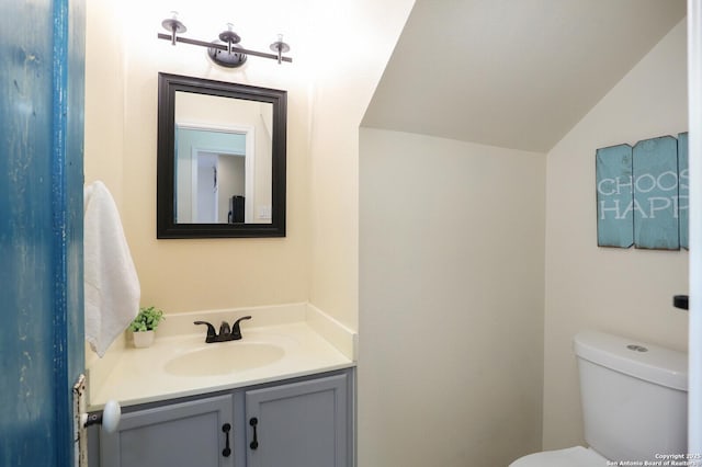 half bath with vanity, lofted ceiling, and toilet