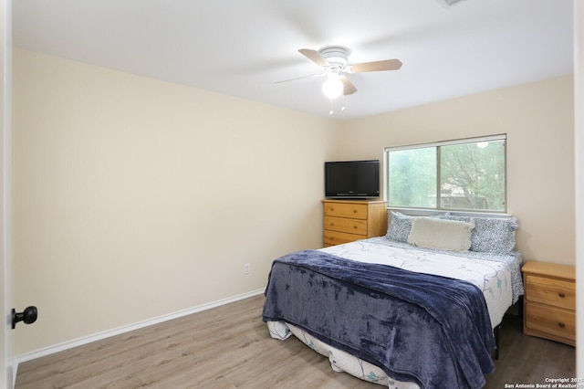 bedroom with a ceiling fan, baseboards, and light wood finished floors