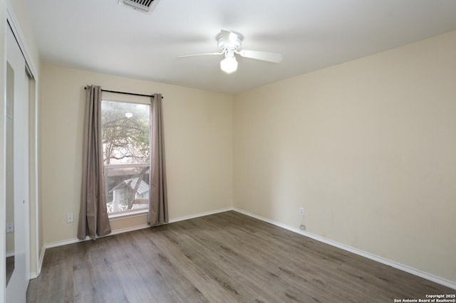 unfurnished room with baseboards, ceiling fan, visible vents, and wood finished floors