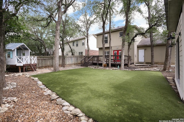 view of yard featuring fence, an outbuilding, and a wooden deck