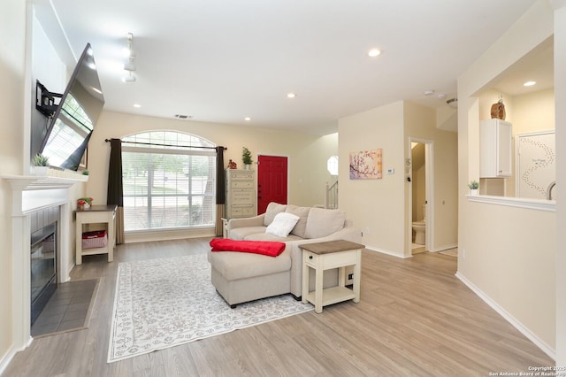 living area with visible vents, a fireplace, baseboards, recessed lighting, and light wood-style flooring