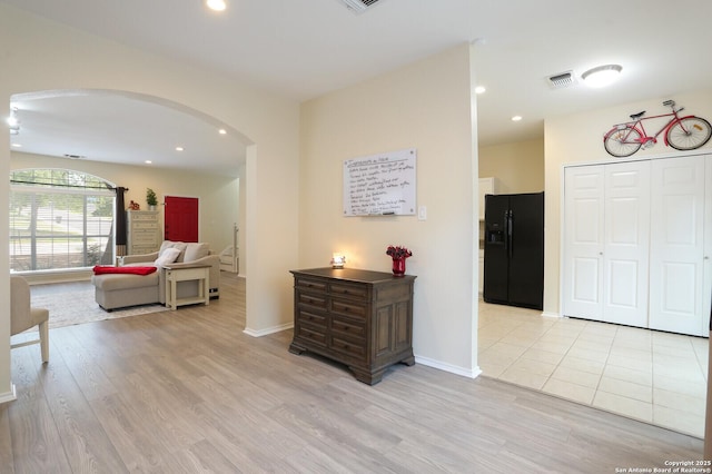 corridor featuring visible vents, arched walkways, baseboards, light wood finished floors, and recessed lighting