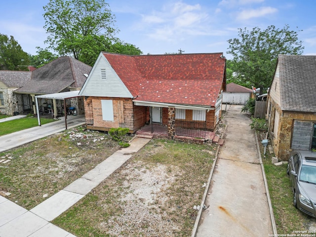 view of front facade with roof with shingles, covered porch, and concrete driveway