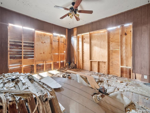 misc room with ceiling fan and wooden walls
