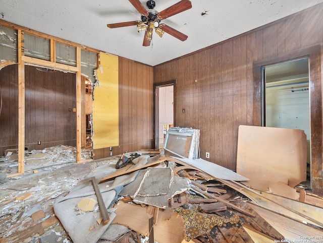 interior space featuring wooden walls and ceiling fan