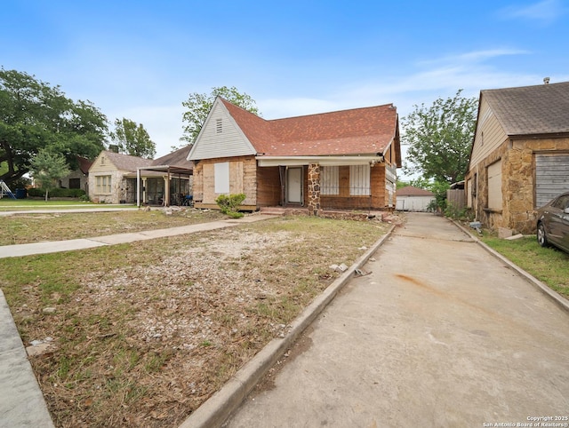 view of front of home with covered porch, brick siding, driveway, and a shingled roof