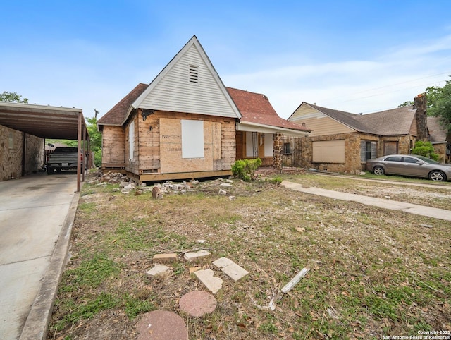 view of front of home with driveway, a shingled roof, and a carport