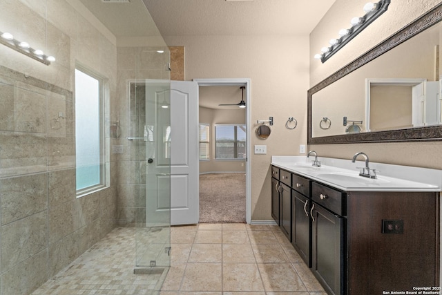 bathroom featuring double vanity, a sink, ceiling fan, and a stall shower