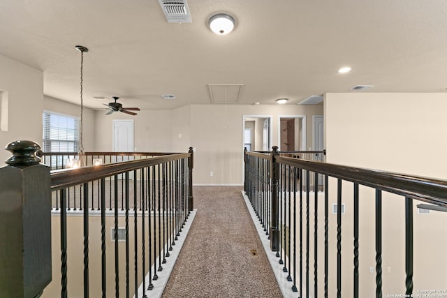 hallway featuring attic access, carpet flooring, and visible vents