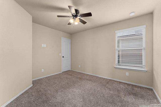 carpeted empty room featuring baseboards and ceiling fan