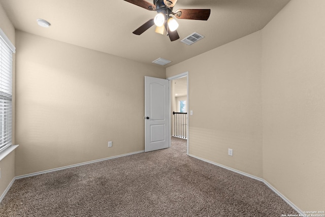 spare room featuring a healthy amount of sunlight, carpet floors, a ceiling fan, and visible vents