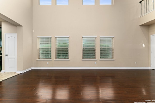 unfurnished living room with plenty of natural light, a high ceiling, and hardwood / wood-style floors