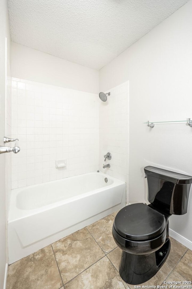 full bath featuring tile patterned flooring, bathtub / shower combination, toilet, and a textured ceiling