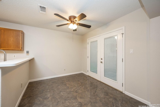 unfurnished dining area featuring visible vents, baseboards, a textured ceiling, french doors, and a ceiling fan