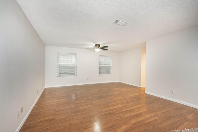 spare room featuring a textured ceiling, a ceiling fan, baseboards, wood finished floors, and visible vents
