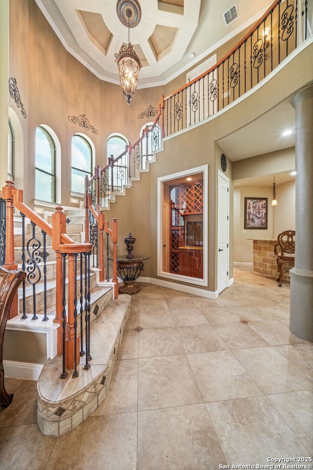 tiled foyer with a healthy amount of sunlight, a high ceiling, stairs, and visible vents