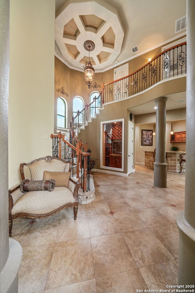 interior space featuring visible vents, crown molding, stairs, a high ceiling, and coffered ceiling