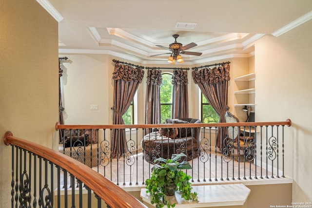 interior space featuring crown molding, a ceiling fan, a tray ceiling, and visible vents