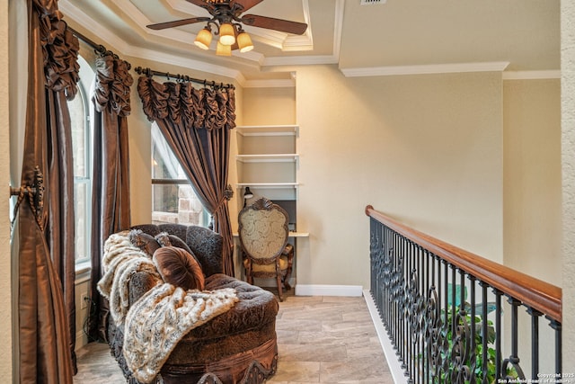 living area with crown molding, a ceiling fan, baseboards, and a raised ceiling
