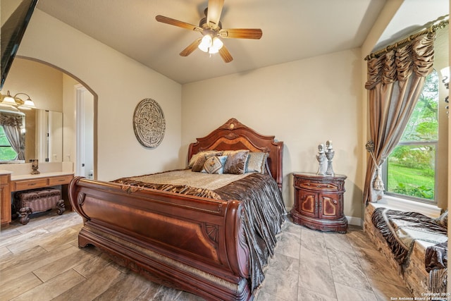 bedroom with arched walkways and a ceiling fan