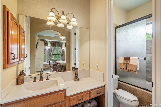 bathroom with vanity, a textured wall, ceiling fan with notable chandelier, and toilet
