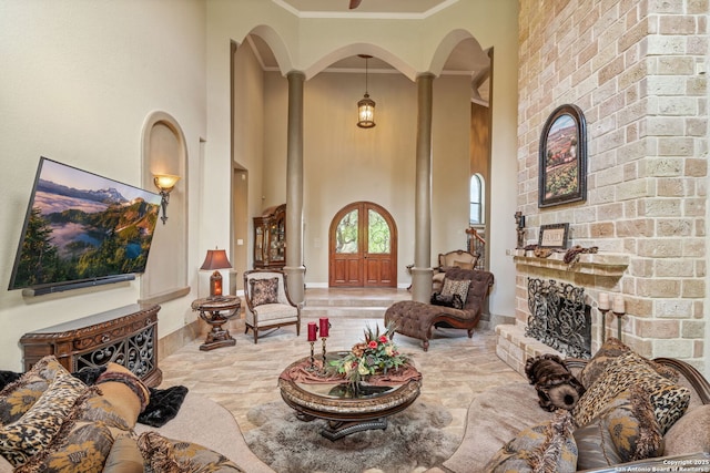 living room with arched walkways, a high ceiling, ornate columns, and a fireplace