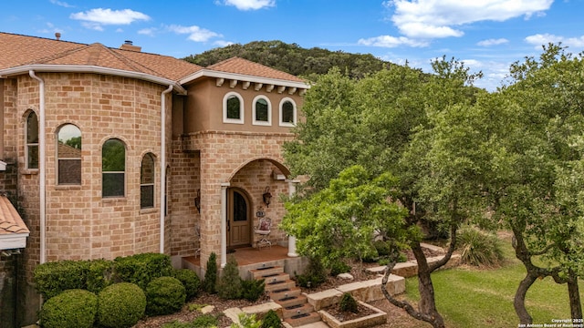 view of front of house featuring a chimney, a shingled roof, stucco siding, and stone siding