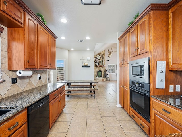 kitchen with dark stone countertops, light tile patterned floors, backsplash, visible vents, and black appliances