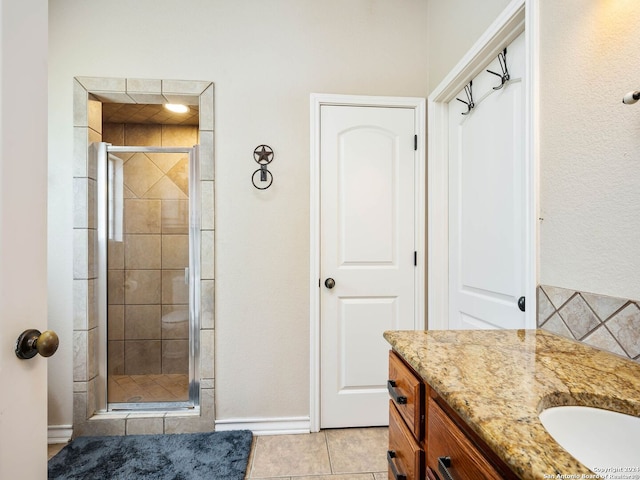 bathroom featuring vanity, baseboards, tile patterned flooring, and a stall shower