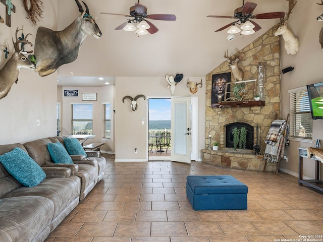 living area with ceiling fan, high vaulted ceiling, a stone fireplace, recessed lighting, and baseboards