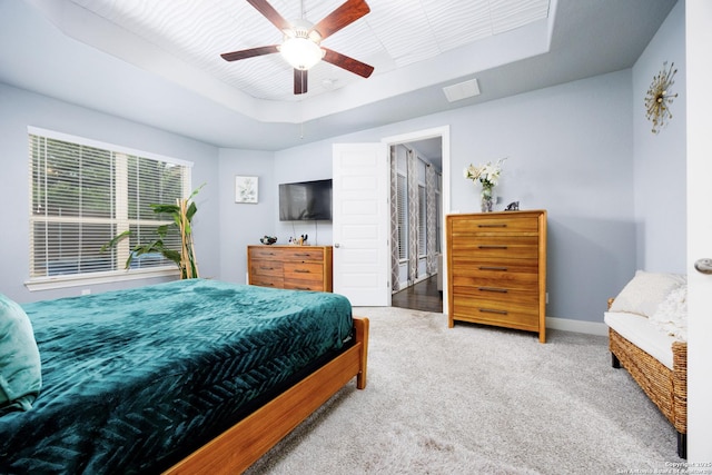 bedroom with carpet floors, a ceiling fan, baseboards, a tray ceiling, and visible vents