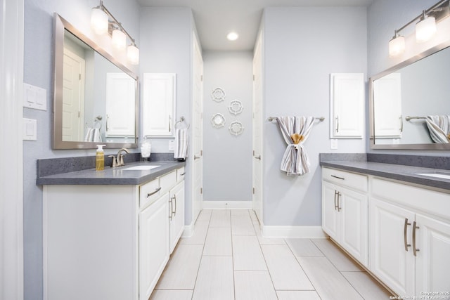 bathroom with recessed lighting, baseboards, two vanities, and a sink