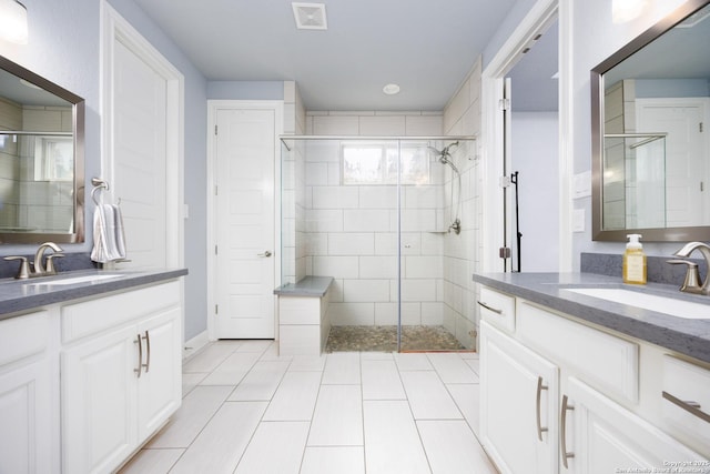 bathroom with a sink, two vanities, a stall shower, and visible vents